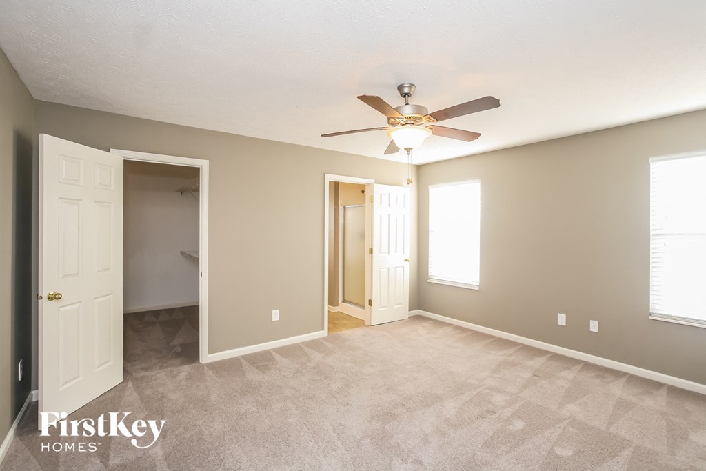an empty living room with a ceiling fan and a door to a closet