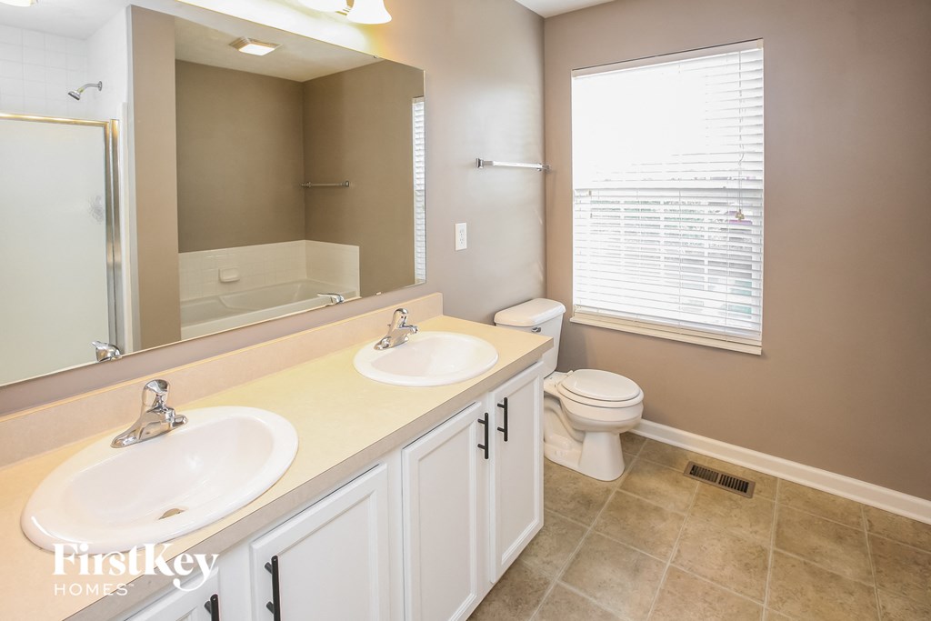 a bathroom with two sinks and a toilet and a large mirror
