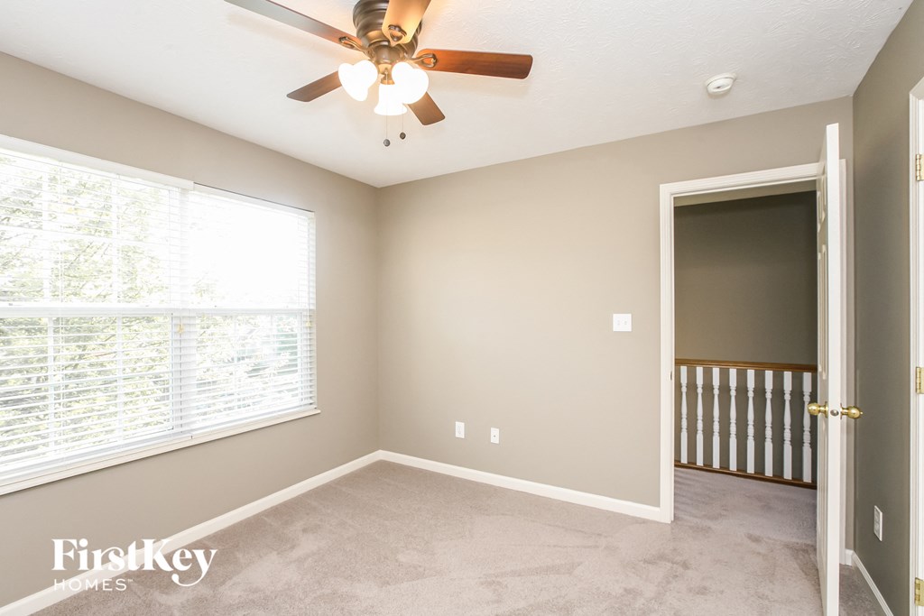 an empty room with a ceiling fan and a large window