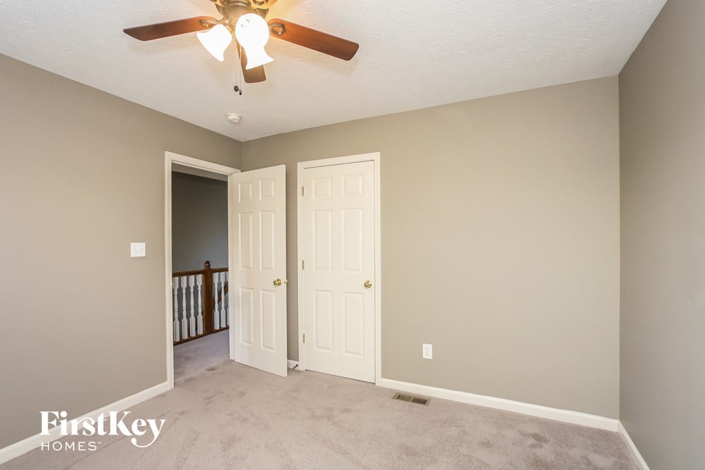 a living room with a ceiling fan and a door to a staircase