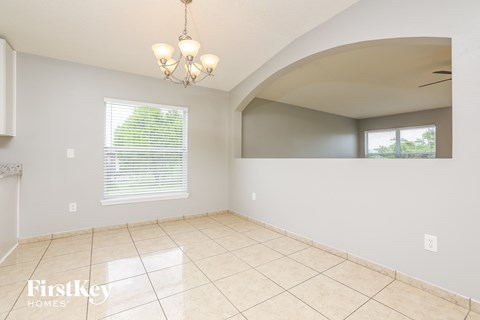 an empty dining room with a large tile floor and a window