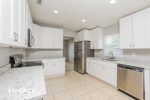 a white kitchen with white cabinets and stainless steel appliances