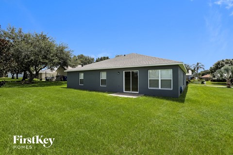 a small gray house in a grassy yard with trees