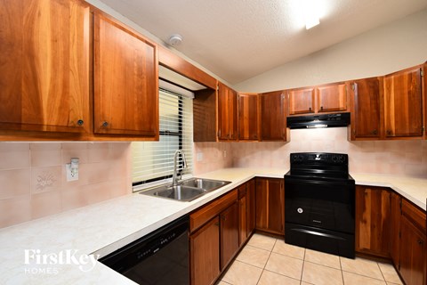 A kitchen with wooden cabinets and a black dishwasher.
