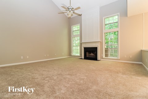 A spacious living room with a fireplace and a ceiling fan.