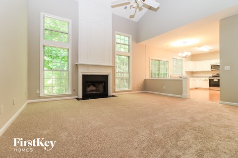 A spacious living room with a fireplace and a ceiling fan.