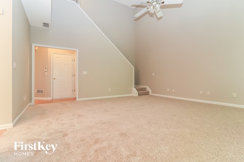 A spacious room with a carpeted floor and a ceiling fan.
