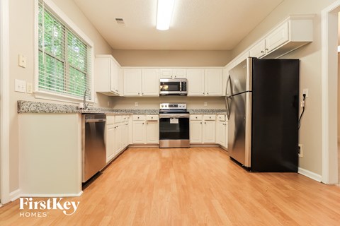 A kitchen with a black refrigerator and wooden floors.