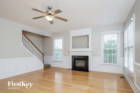 an empty living room with a fireplace and a ceiling fan