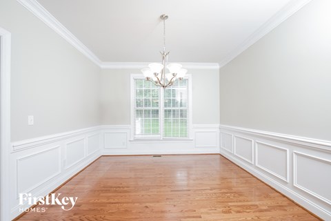 an empty dining room with white wainscoting and a chandelier