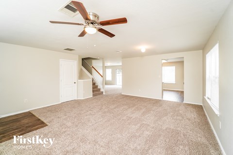 A spacious room with a fan and carpeted floor.
