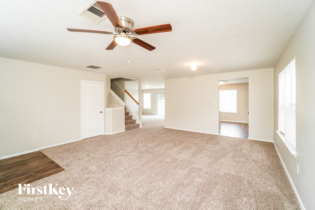 A spacious room with a fan and carpeted floor.