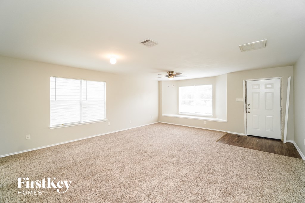 A spacious room with a carpeted floor and a ceiling fan.
