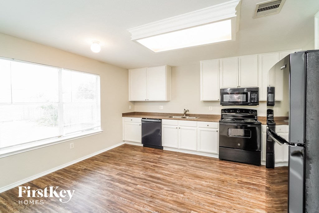 A kitchen with wooden floors and white cabinets.