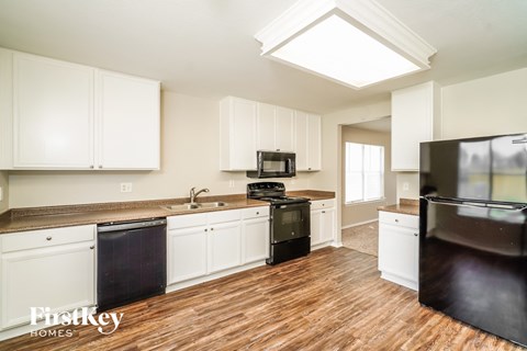 A kitchen with white cabinets and a black fridge.