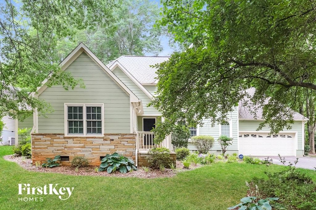 A house with a green lawn and trees in the background.