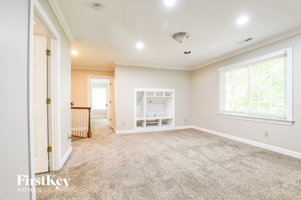 A spacious room with a carpeted floor and a window letting in natural light.