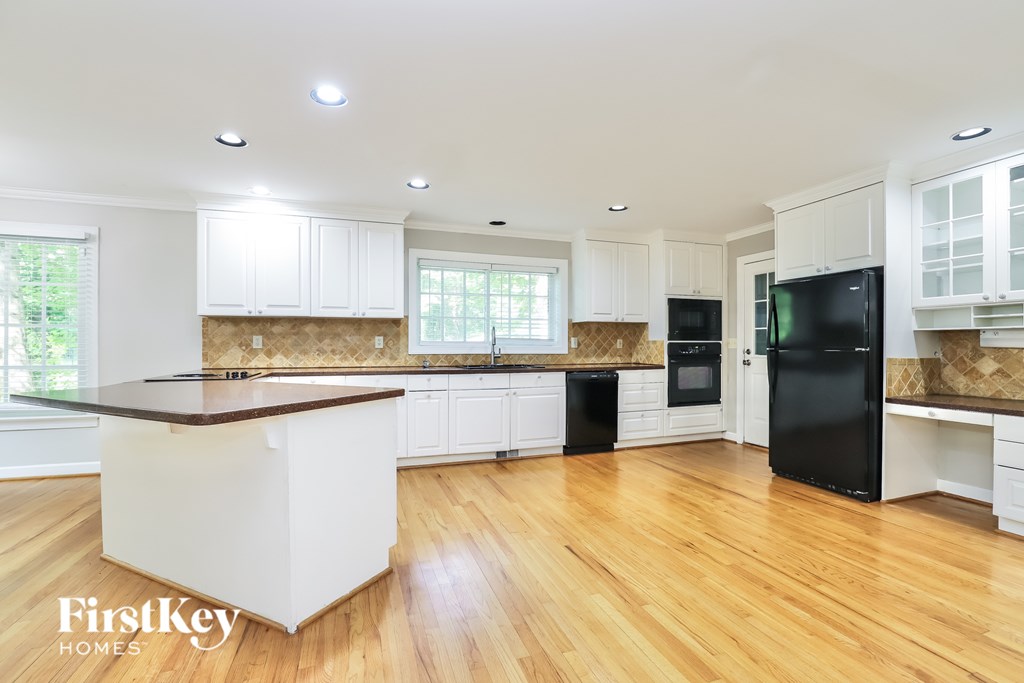 A kitchen with wooden floors and white cabinets.