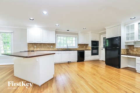 A kitchen with wooden floors and white cabinets.