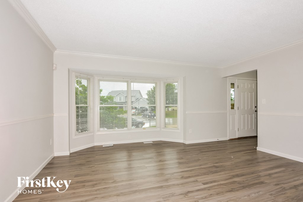 a living room with white walls and wood floors and large windows