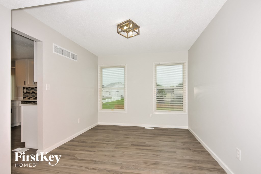 the living room of an empty house with wood flooring and two windows