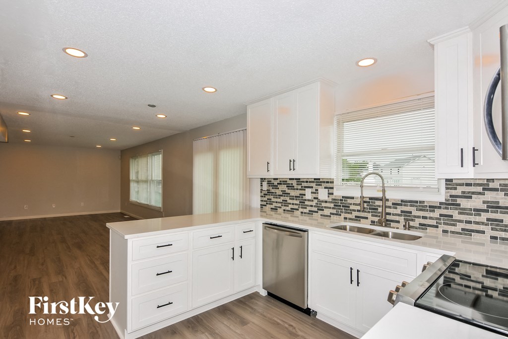 a white kitchen with stainless steel appliances and white cabinets