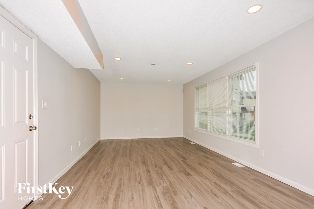 a spacious living room with hardwood floors and a large window