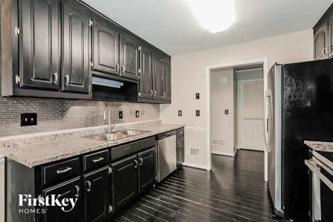 a kitchen with black cabinets and granite counter tops and a sink