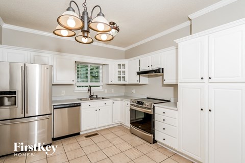 A kitchen with white cabinets and a stainless steel refrigerator.