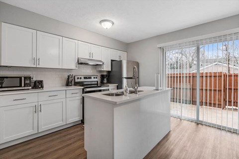 a white kitchen with a large window and a sink