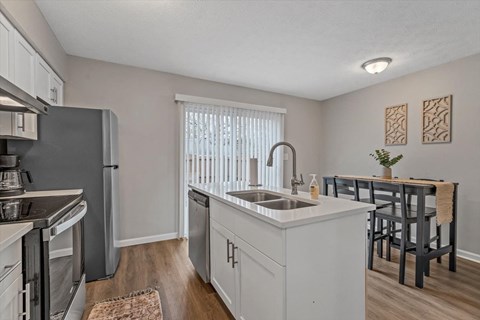 an open kitchen and dining room with a stainless steel refrigerator and sink