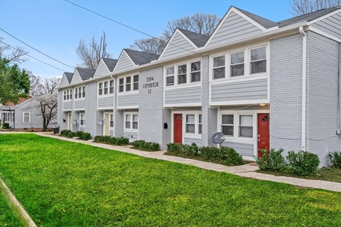 a row of white houses with red doors on a sidewalk