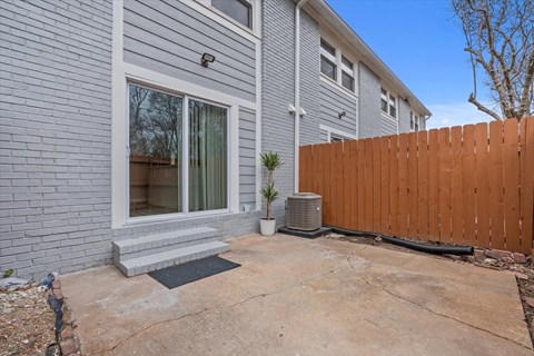 a white house with a wooden fence and a patio in front of it