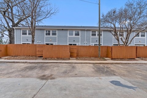 the building in which the apartment is located is shown behind a wooden fence