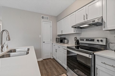 an empty kitchen with white cabinets and stainless steel appliances