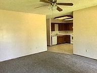 an empty living room with a ceiling fan