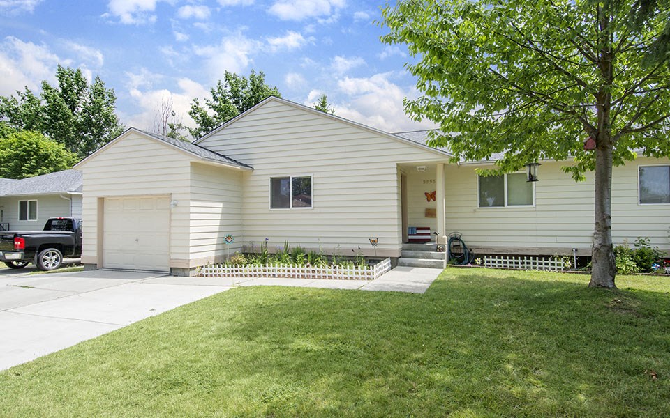 a white house with a driveway and a tree
