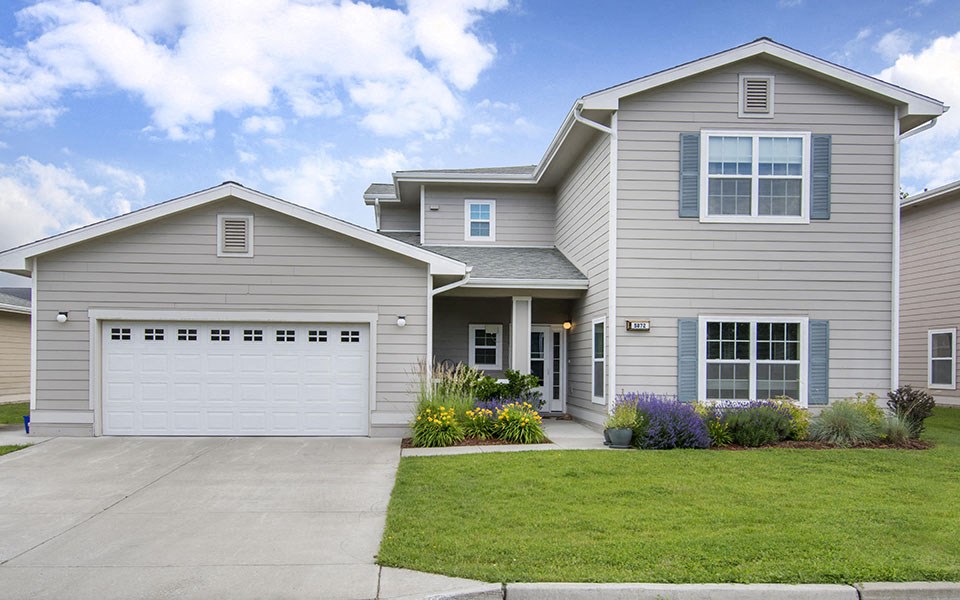a gray house with a driveway and a lawn