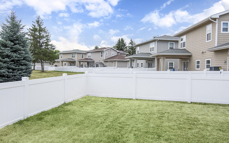 a white fence in a yard in front of houses
