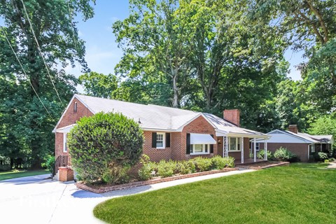 the front of a brick house with a lawn and a driveway
