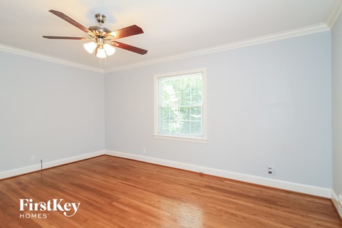 a bedroom with wood floors and a ceiling fan