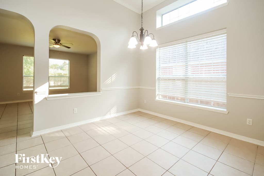 an empty dining room with a large window and white tile flooring