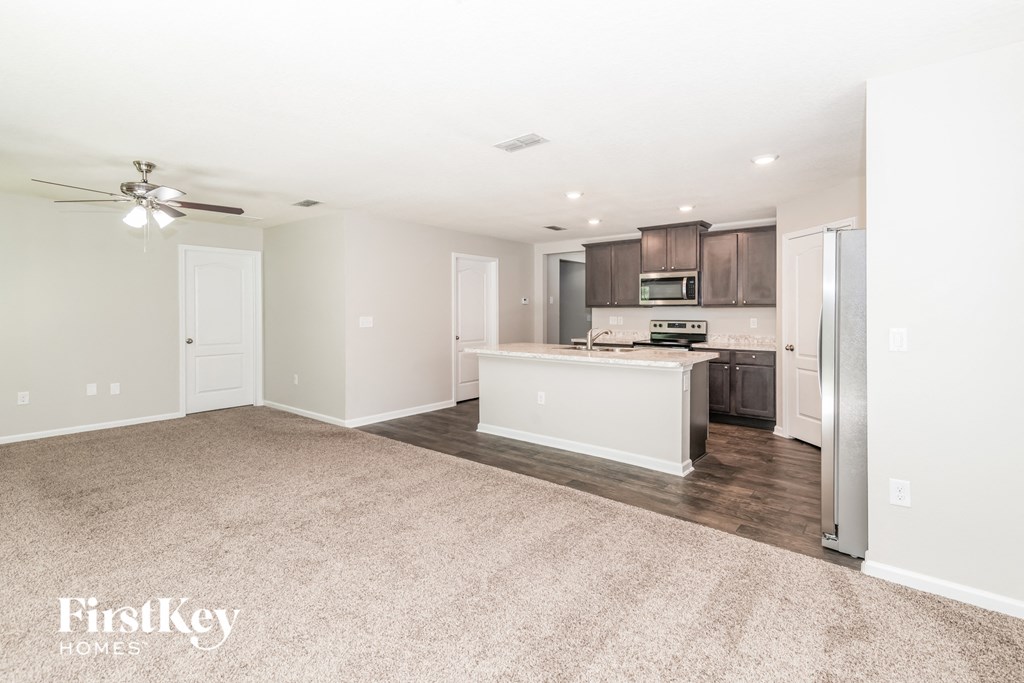 a living room with a kitchen and a ceiling fan
