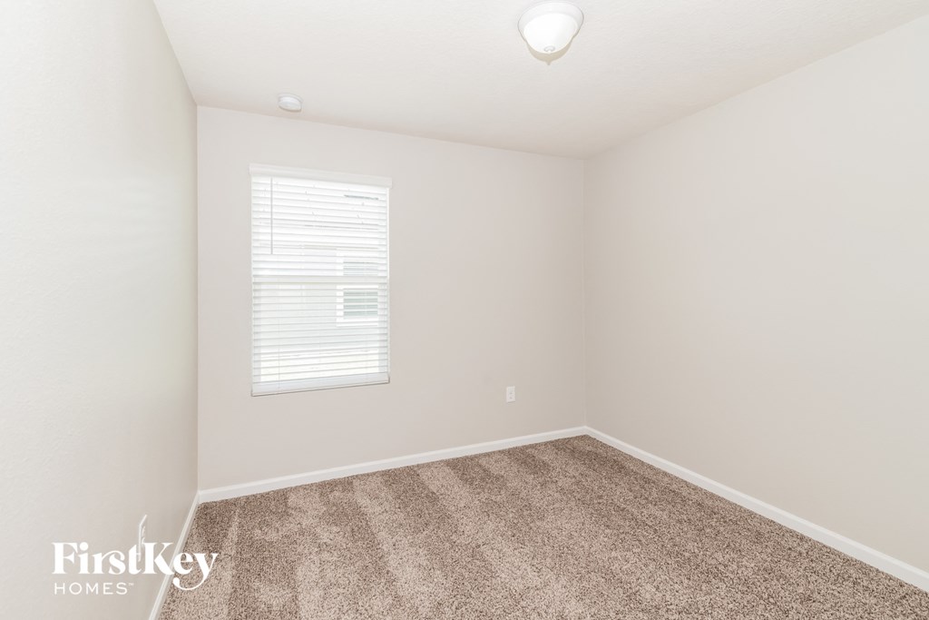 a spacious room with carpet and a window