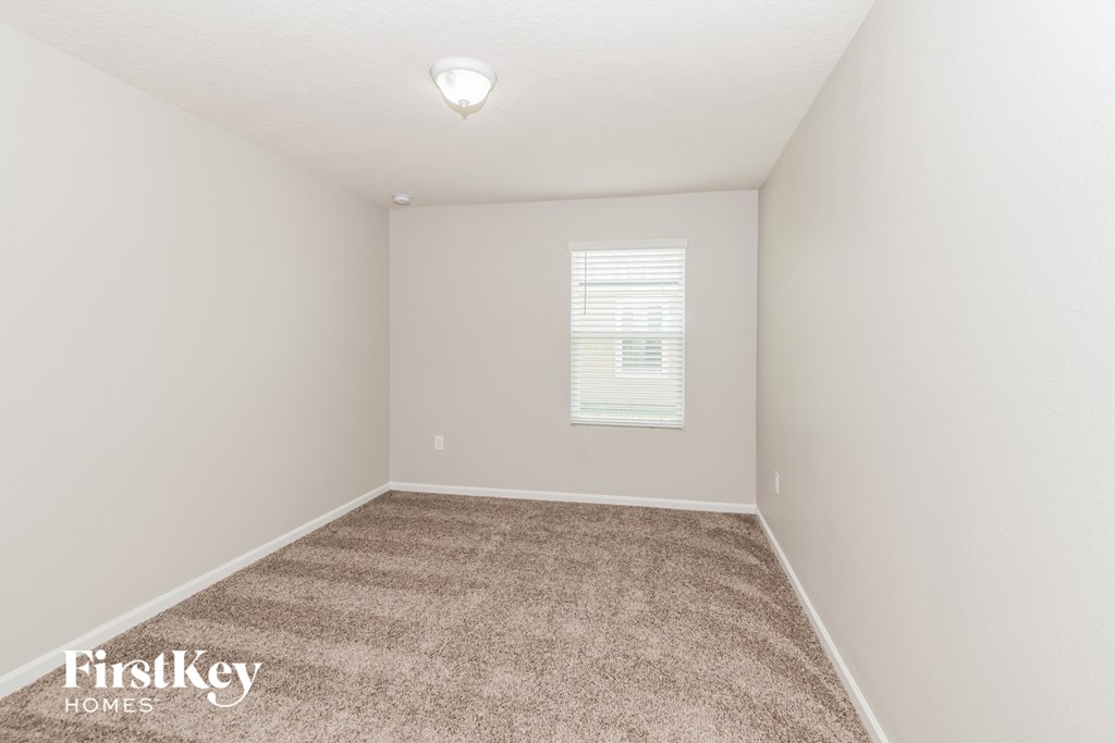 a spacious room with carpet and a window