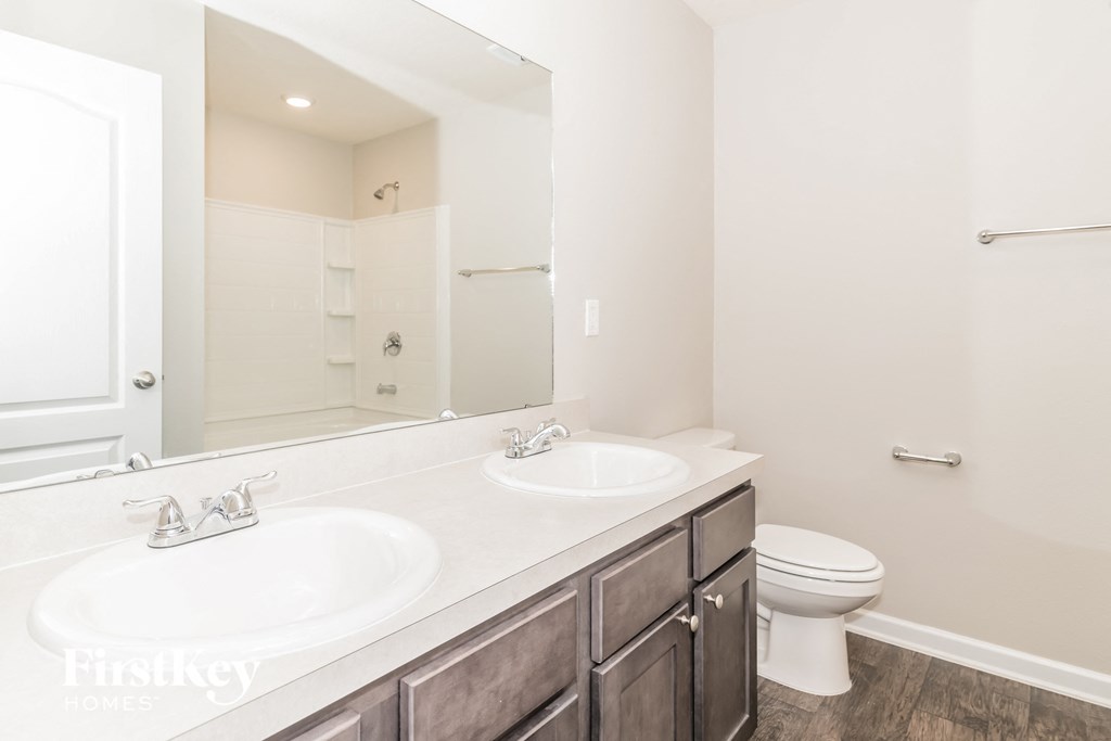 a bathroom with two sinks and a toilet and a large mirror