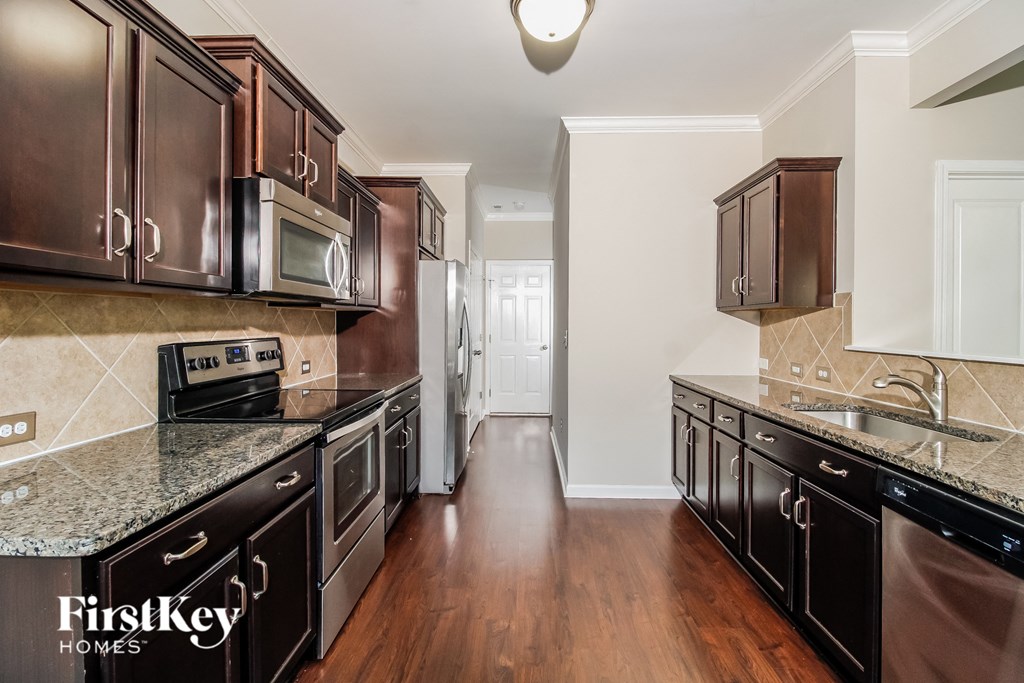 a kitchen with dark wood cabinets and granite counter tops and stainless steel appliances