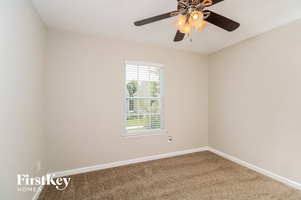 a bedroom with a ceiling fan and a carpet