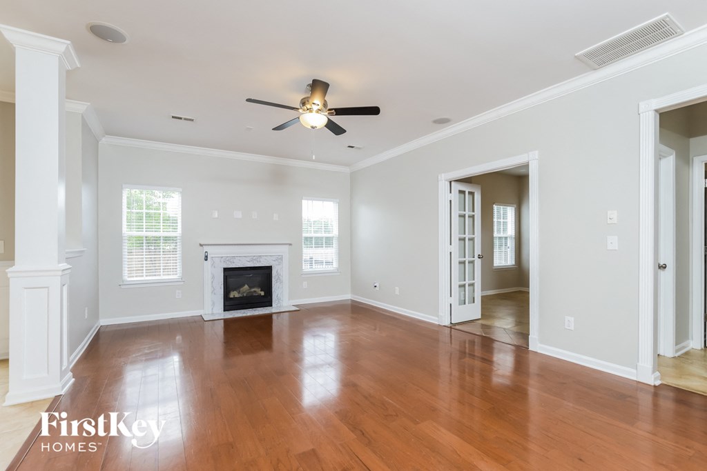 an empty living room with a fireplace and a ceiling fan