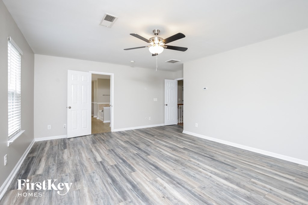 an empty living room with white walls and a ceiling fan
